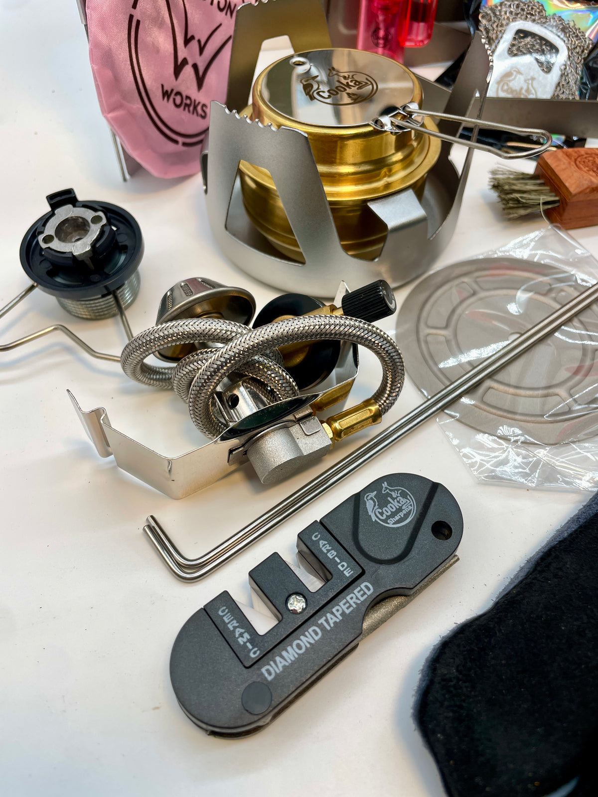 Close-up of the Big Kahuna Kit's butane burner adaptor with braided hose, Burn'a metho stove and Sharpen'a diamond knife sharpener